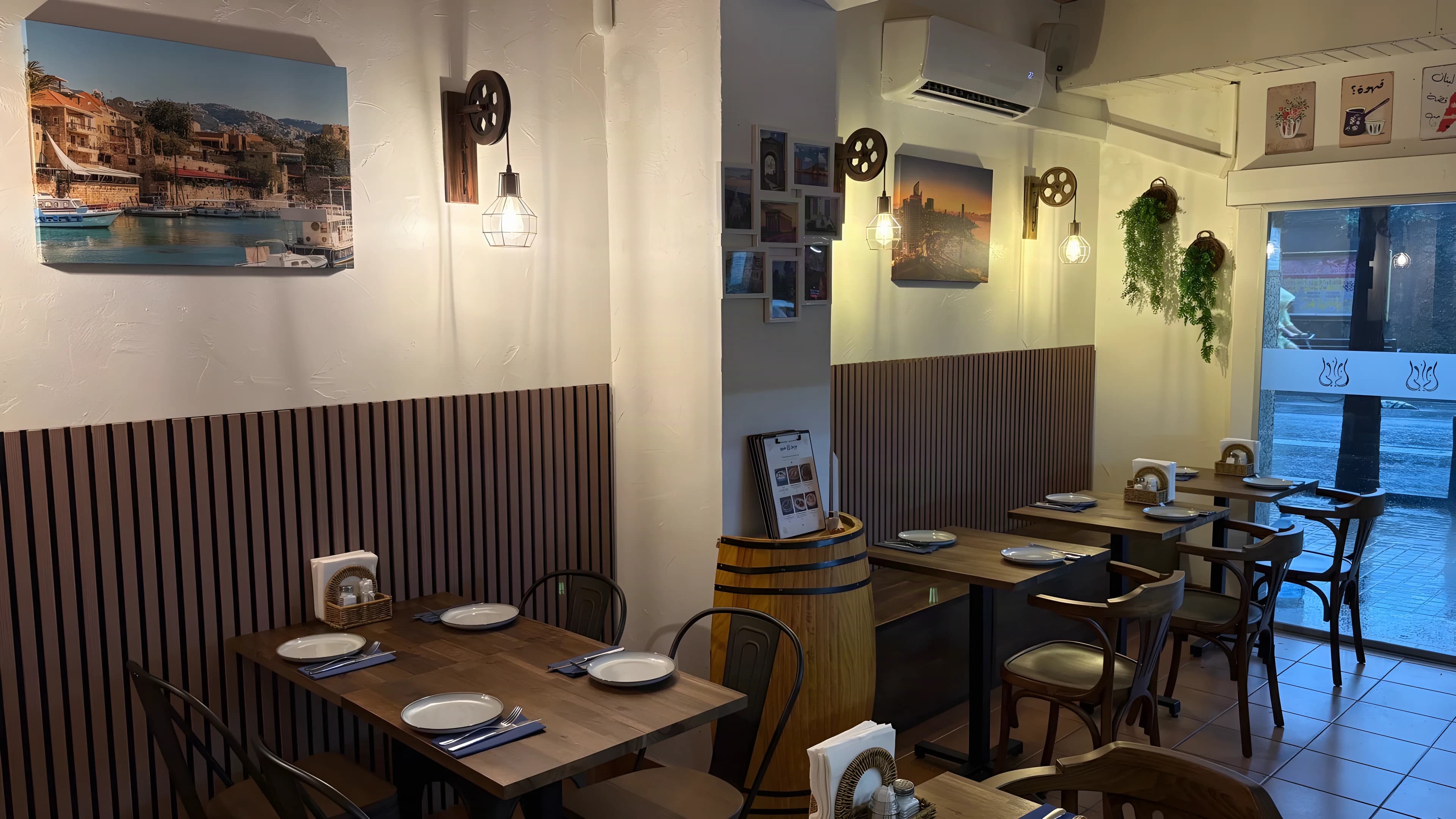 The Layali Beirut dining room, with wooden tables and chairs, hanging lamps and photographs of Beirut.